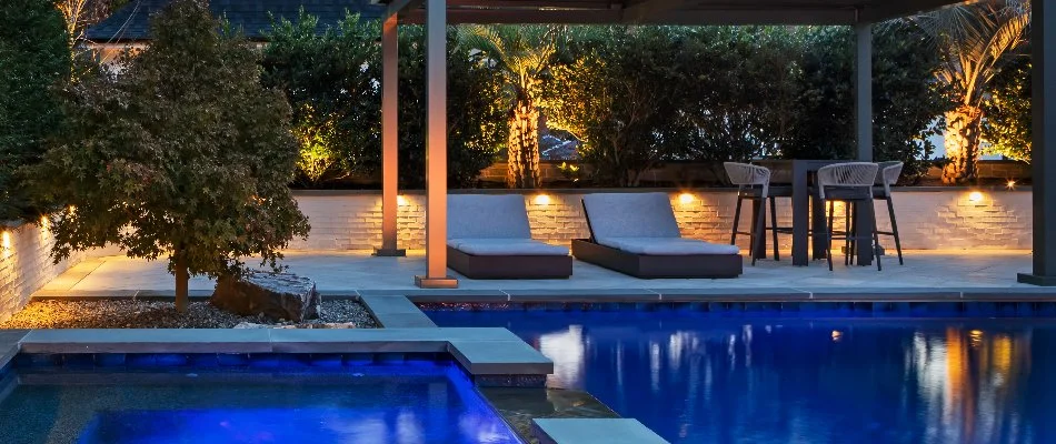 Pool deck in Cary, NC, with lounge chairs and landscape lighting.