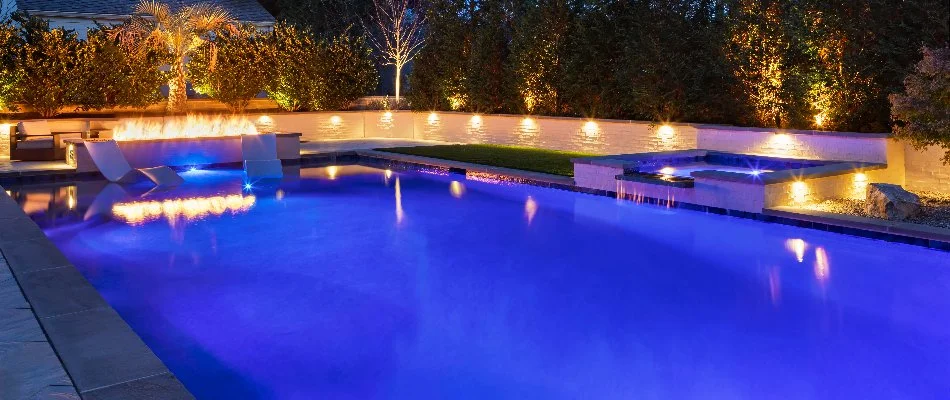 Illuminated pool with lights and fire table in Cary, NC.